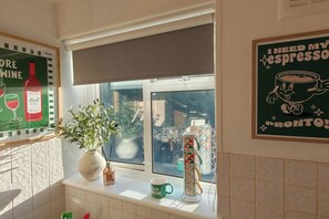 A kitchen with a window, a potted plant, and various kitchenware. - Ladbroke Grove 1 Bed Flat | Fast Wi‑Fi | Sleeps 4 (Greater London)
