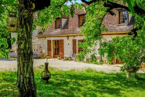 A traditional stone house with a gravel driveway, a wooden chair, and a hanging lantern. - Under skies that arch from field to forest (Saint-Cernin-de-Labarde)