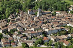 A densely packed village with traditional architecture, including a prominent church with a bell tower. - Under skies that arch from field to forest (Saint-Cernin-de-Labarde)