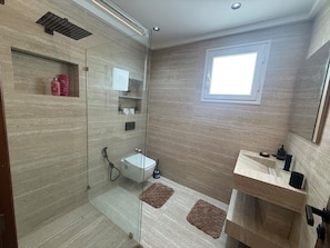 A modern bathroom with a glass-enclosed shower, a white sink, and a small window. - Modern 2-Bedroom Apartment with Balcony Near the Beach (Sousse)