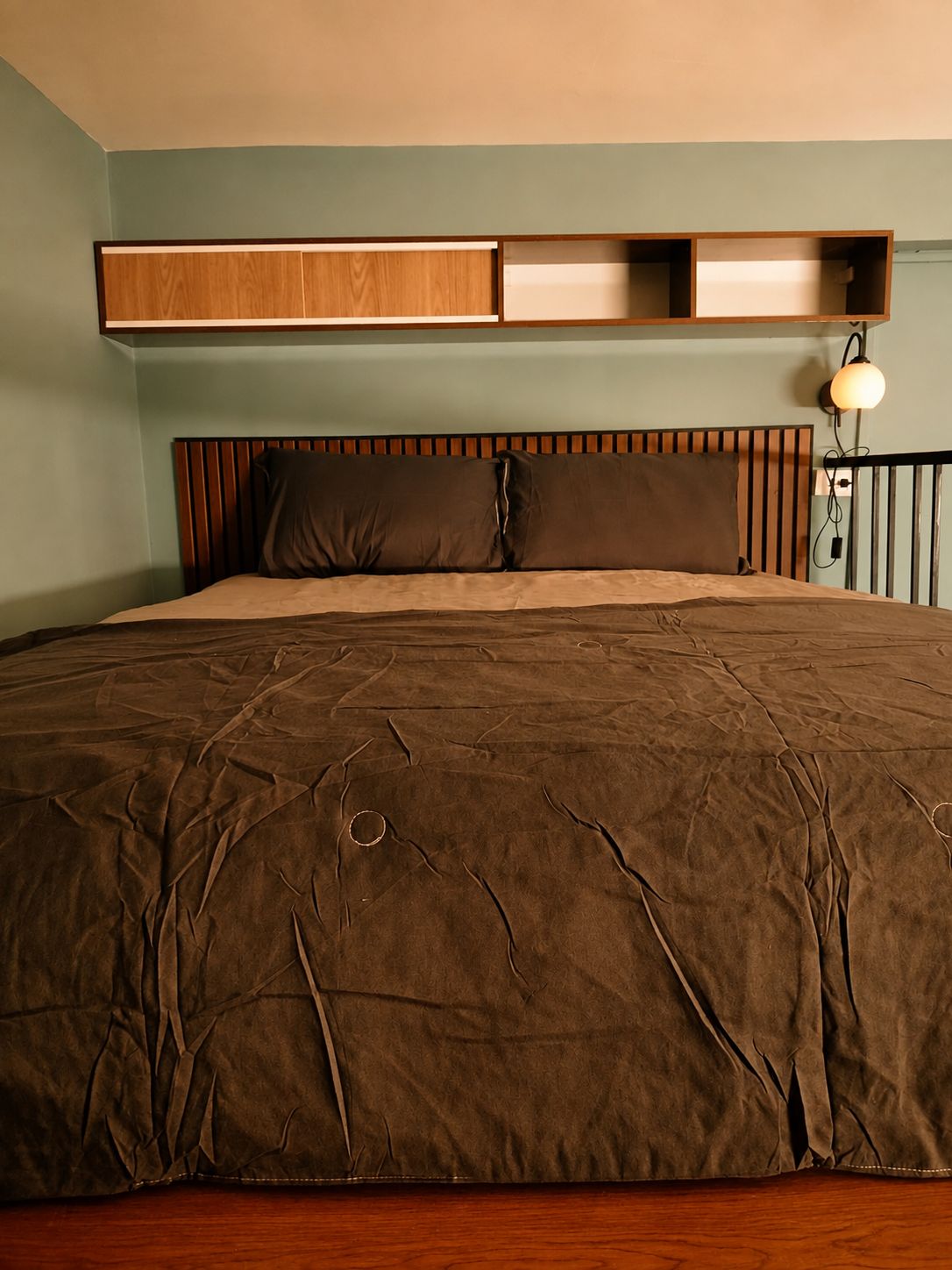 Un dormitorio con una cama grande, cabecero de madera y estante empotrado sobre la cama.