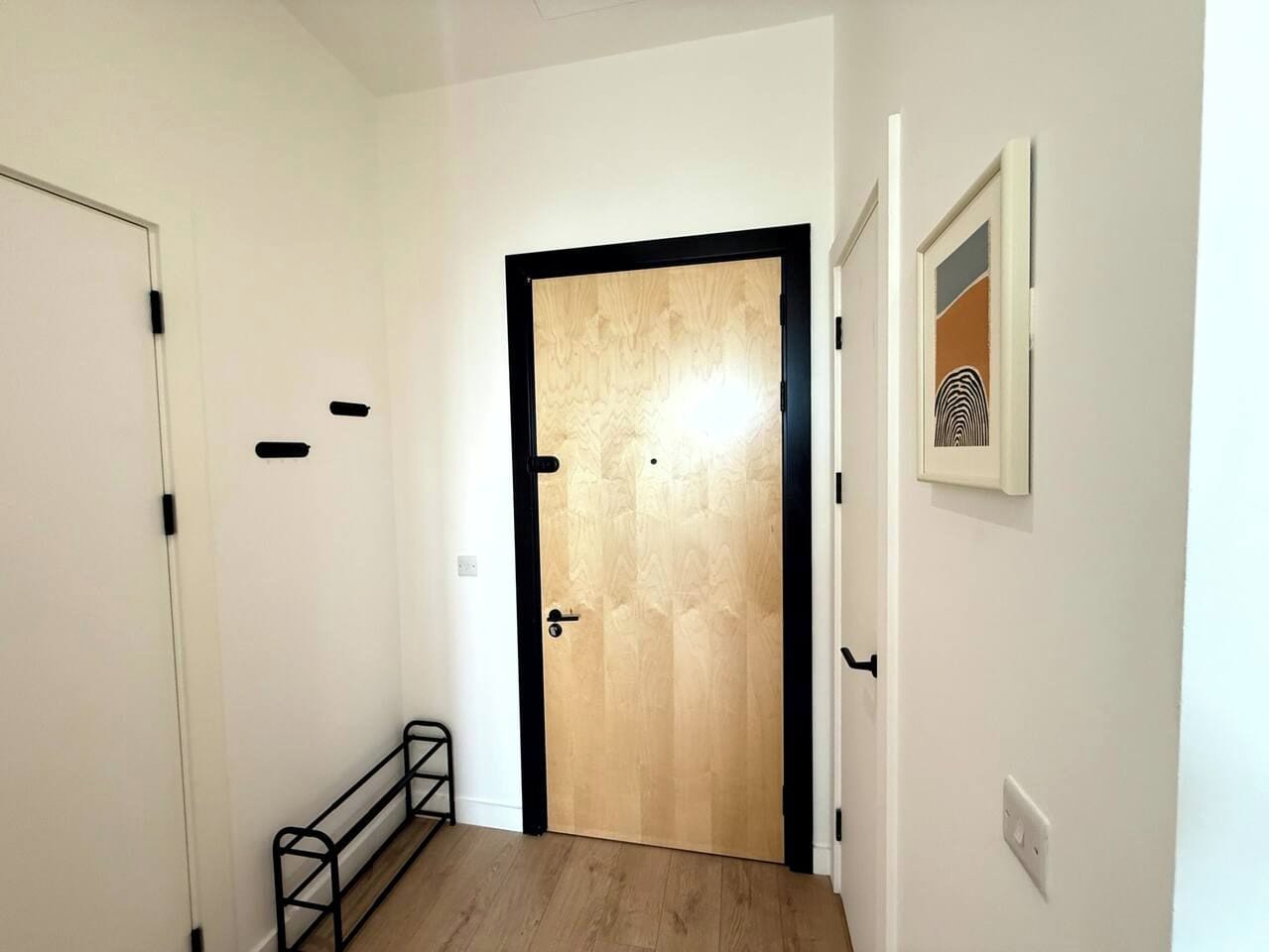 A hallway with a wooden door, a metal bench, and a framed picture on the wall.