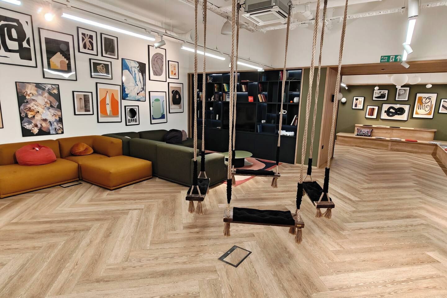 Ein modernes Interieur mit Fischgrätparkett, einer Eckcouch und einem Schaukelbereich mit Seilen.