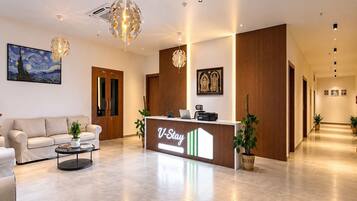 A hotel reception area with a modern design, including a reception desk, a painting, and a chandelier.
