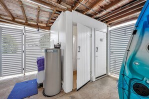 Un garage avec une porte blanche, un lave-linge et un kayak.