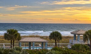 A beachfront view with a pool area, two gazebos, and palm trees. - Unwind Poolside, Walk to Beach! Pensacola Getaway (Pensacola Beach)