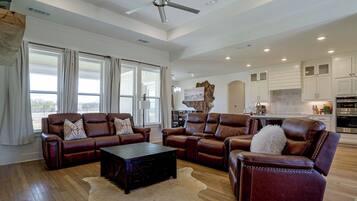 A spacious living room with leather sofas, a coffee table, and a rug.