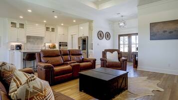A spacious living area with a brown leather sofa set, a coffee table, and a rug.