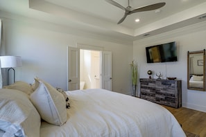 Un dormitorio con una cama, ventilador de techo, televisor y cómoda.