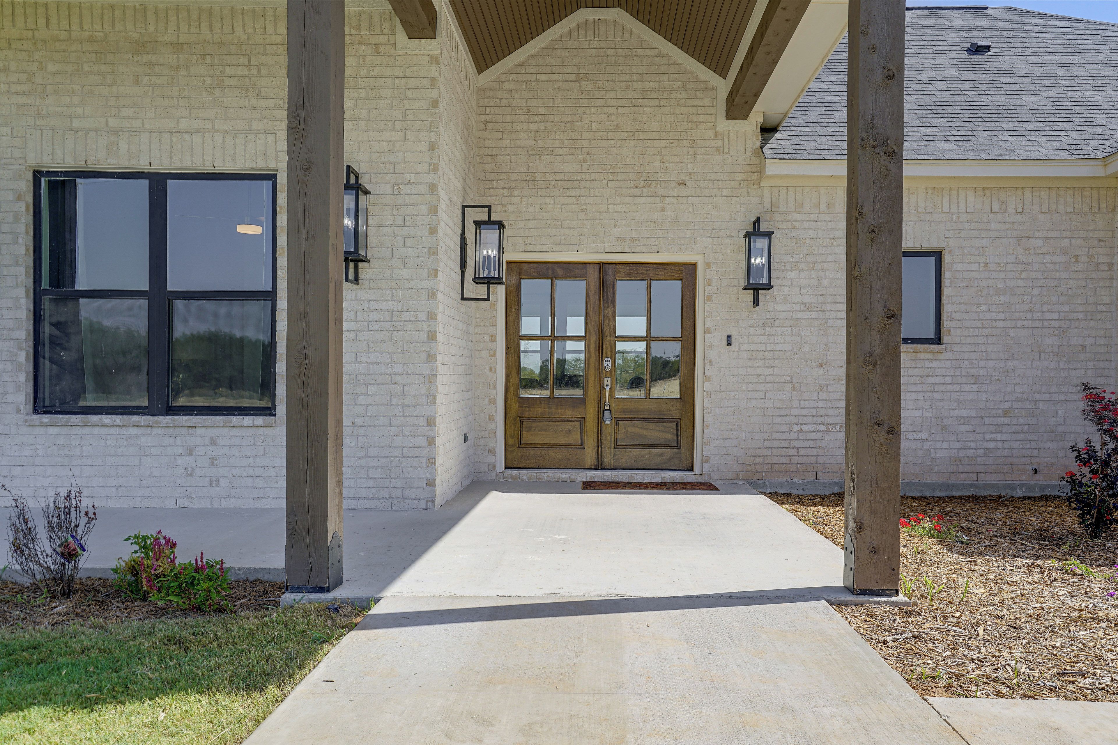 A building with a brick facade, a wooden front door, and two wall-mounted lights.