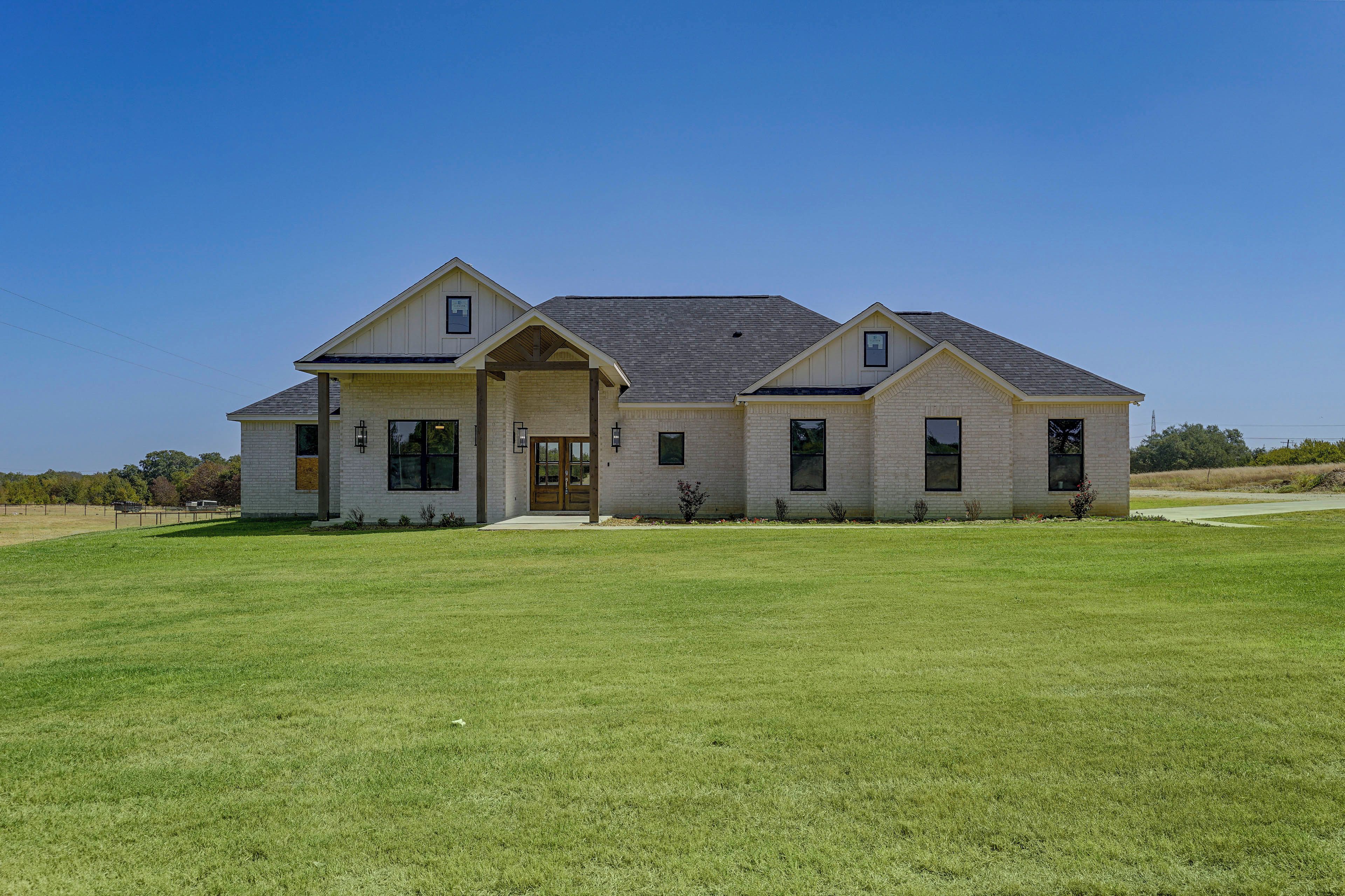 A two-story house with a front porch, a covered entryway, and a large lawn.