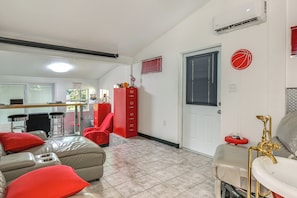A living room with a sofa, a red cabinet, and a door with a window. - 6 Mi to Spanish Springs! Private Unit w/ Projector (Lady Lake)