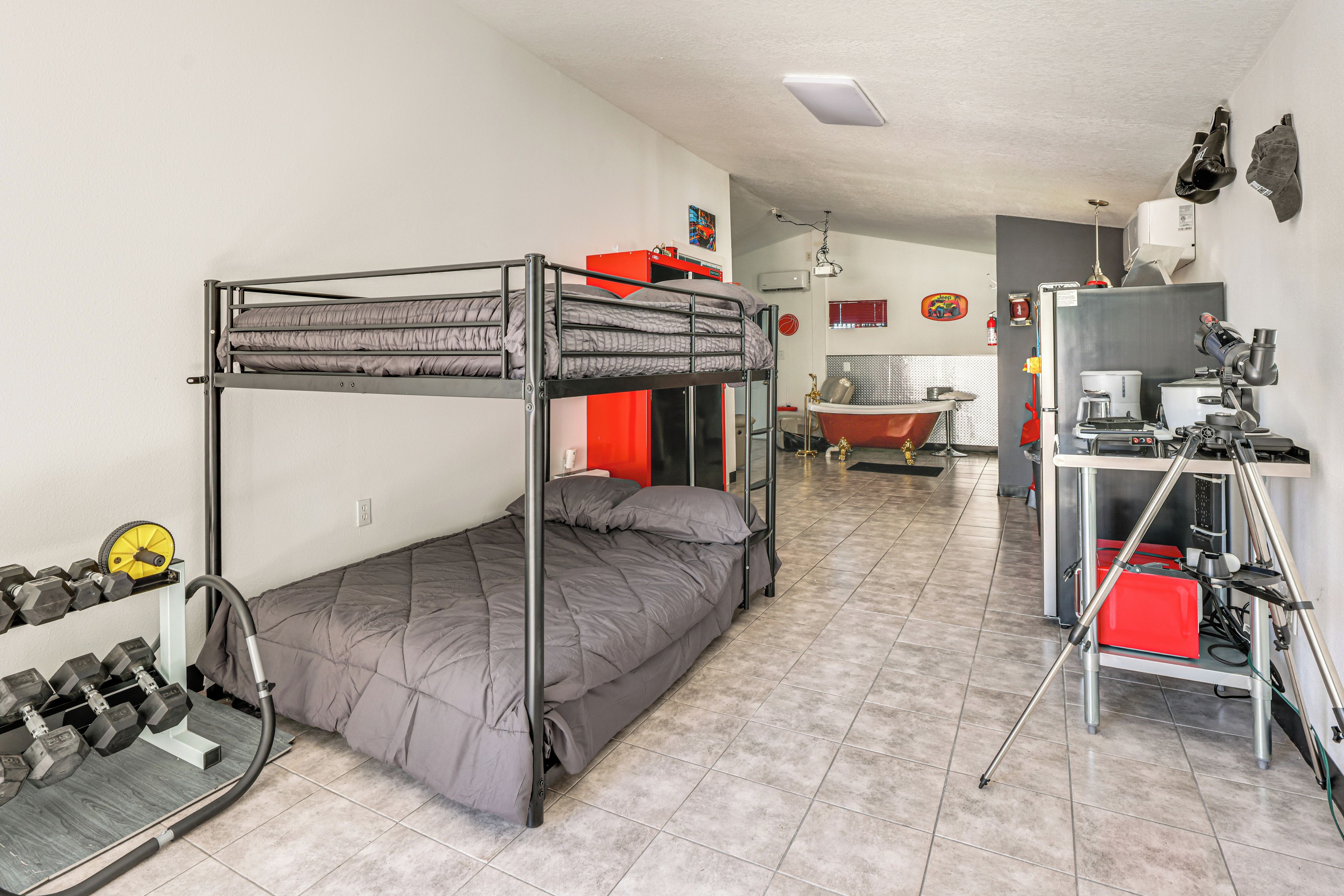 A bunk bed with a desk and a telescope in a room with tiled flooring.