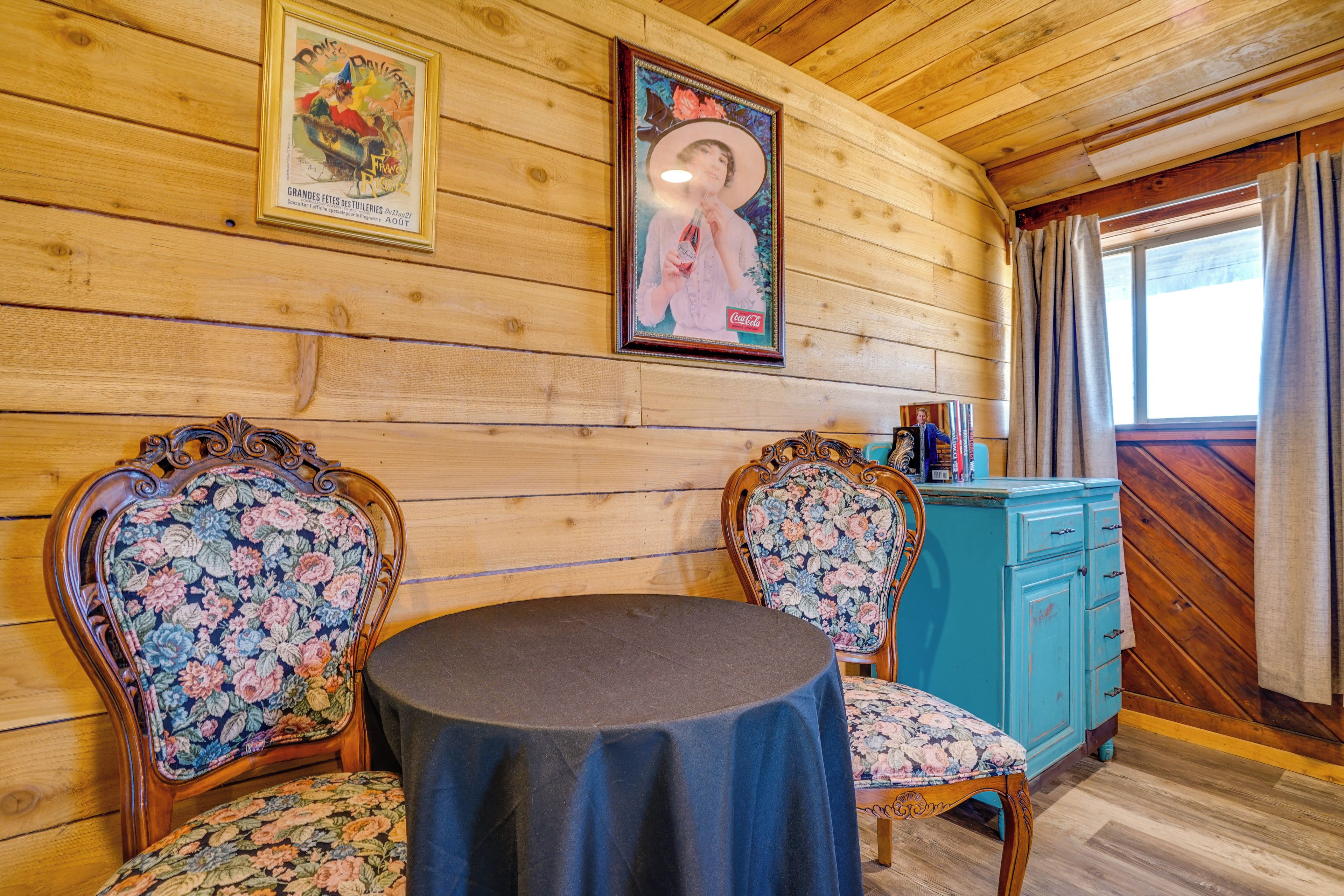 A wooden interior with two ornate chairs, a round table, and a blue cabinet.