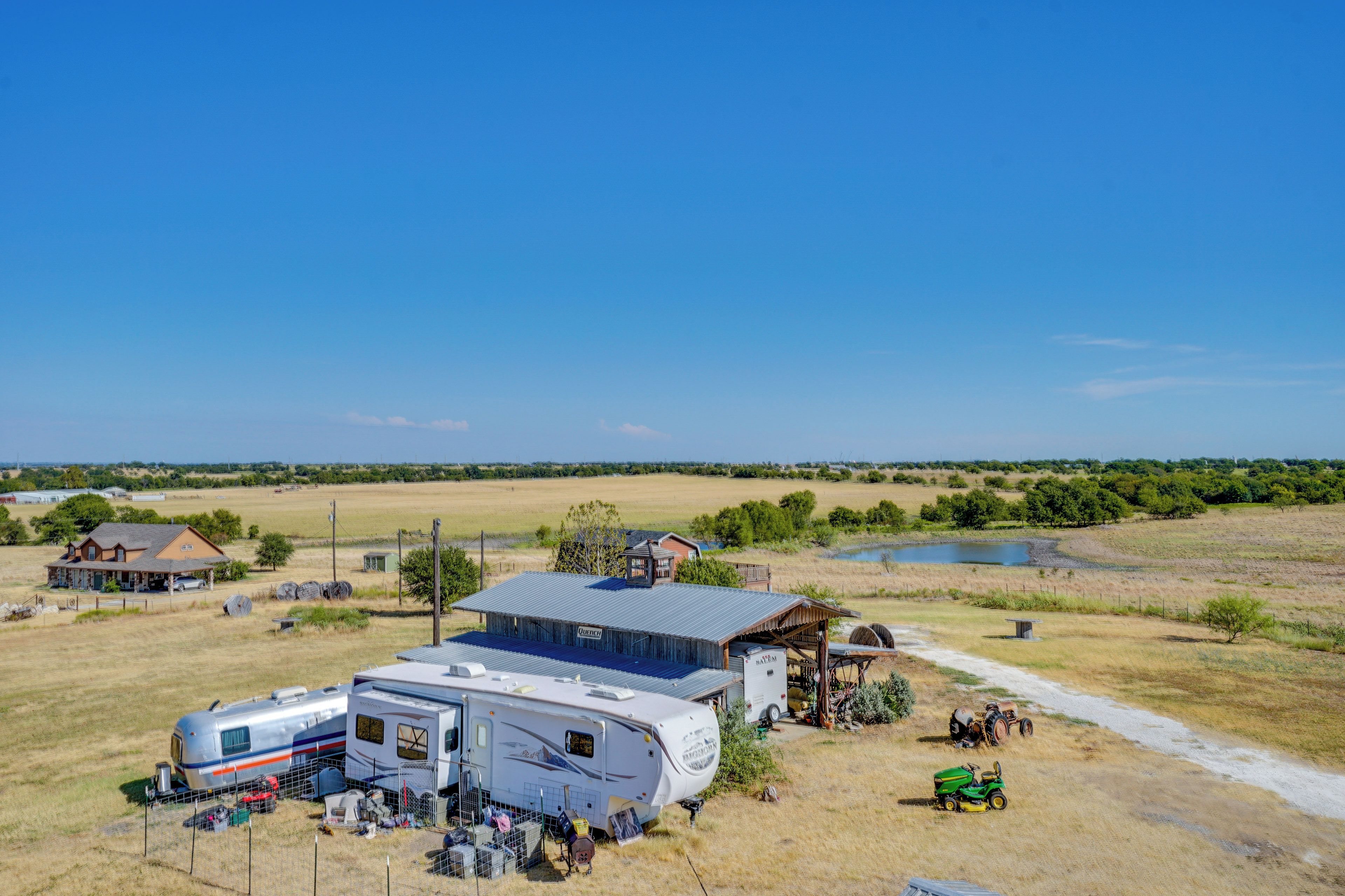 A rural property with a large RV, a barn, and a pond.