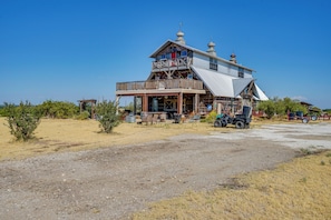A two-story wooden building with a balcony and a covered porch. - 6-acre Barndominium Escape, 6 Mi to Lake Cleburne! (Cleburne)