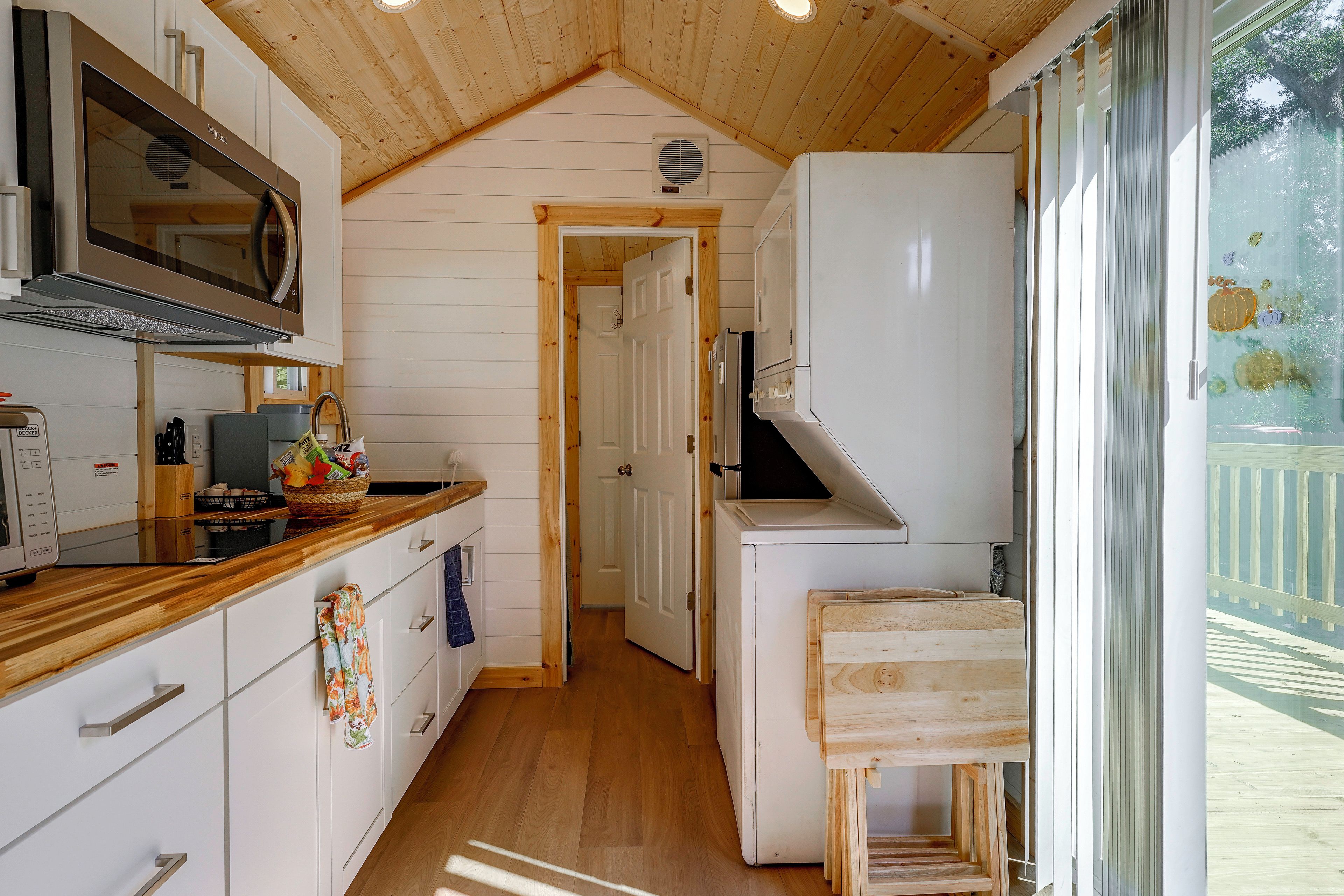 Una cocina con armarios de madera, un microondas y un lavamanos.