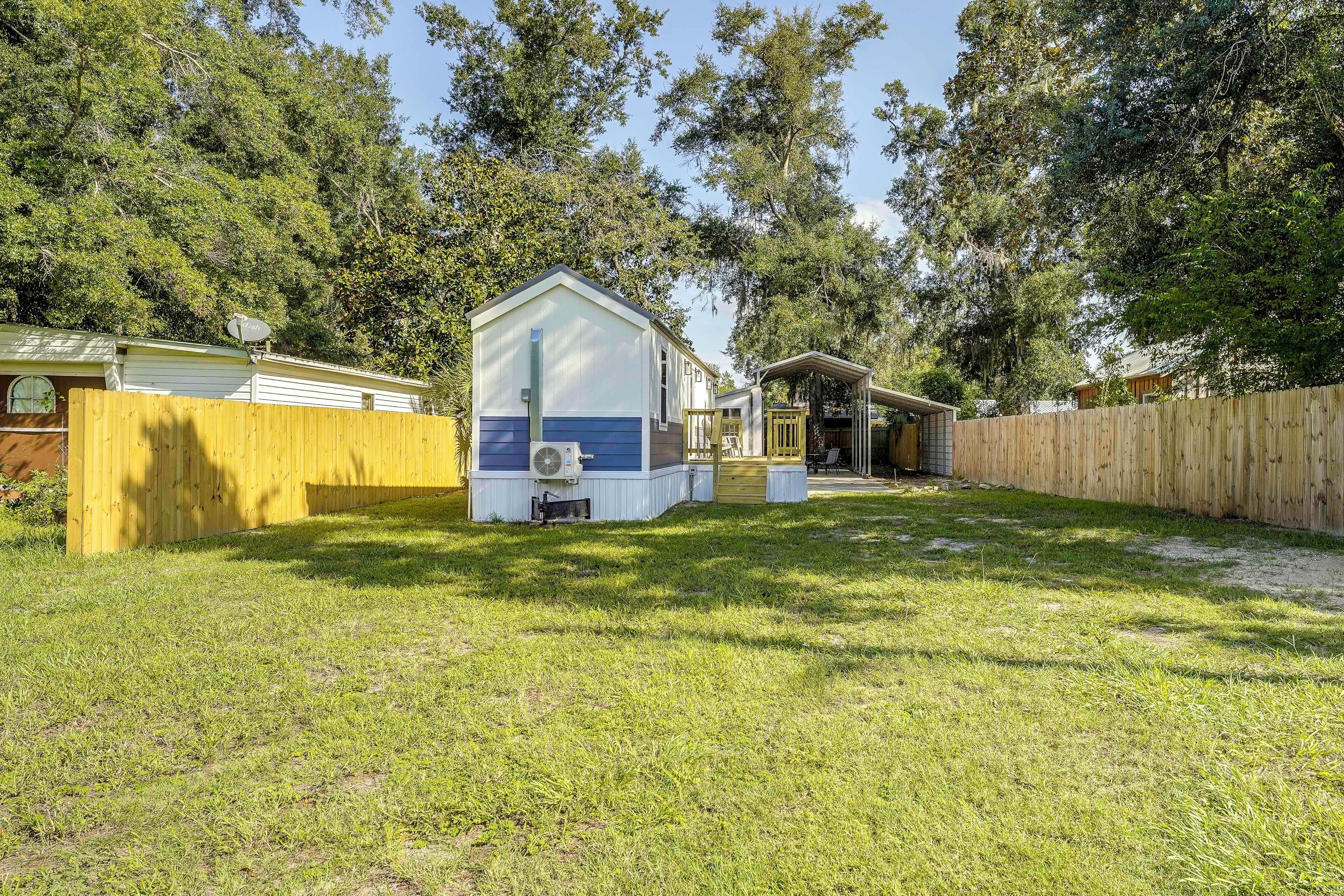 A small, single-story house with a fenced yard, a covered porch, and a satellite dish.