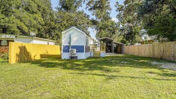 A small, single-story house with a fenced yard, a covered porch, and a satellite dish.