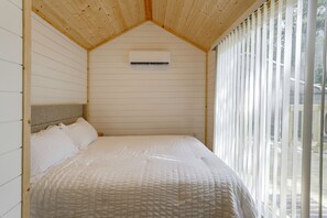 Una habitación con una cama, cabecera y ventana con persianas.