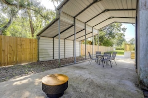 Un patio techado con mesa y sillas, una mesa redonda con tapa y una cerca de madera.