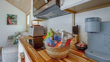 A kitchen with a coffee maker, a basket of coffee bags, and a water dispenser.