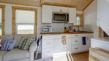 A compact kitchen with a microwave, toaster, and wooden cabinets.