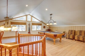 Ein geräumiger Raum mit Pooltisch, Holzböden und einer hohen Decke mit Oberlichtern.