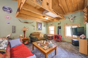 Una sala de estar acogedora con chimenea, televisor y varios objetos decorativos, incluyendo cráneos de animales y un reloj.