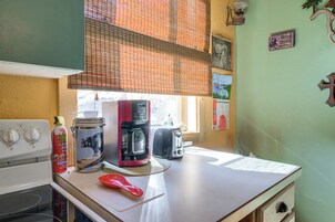 A kitchen with a stove, a coffee maker, a toaster, and a fire extinguisher.