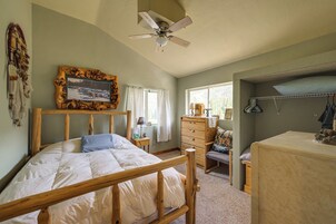 Un dormitorio con una cama de madera, un aparador, un tocador y una ventana con cortinas.