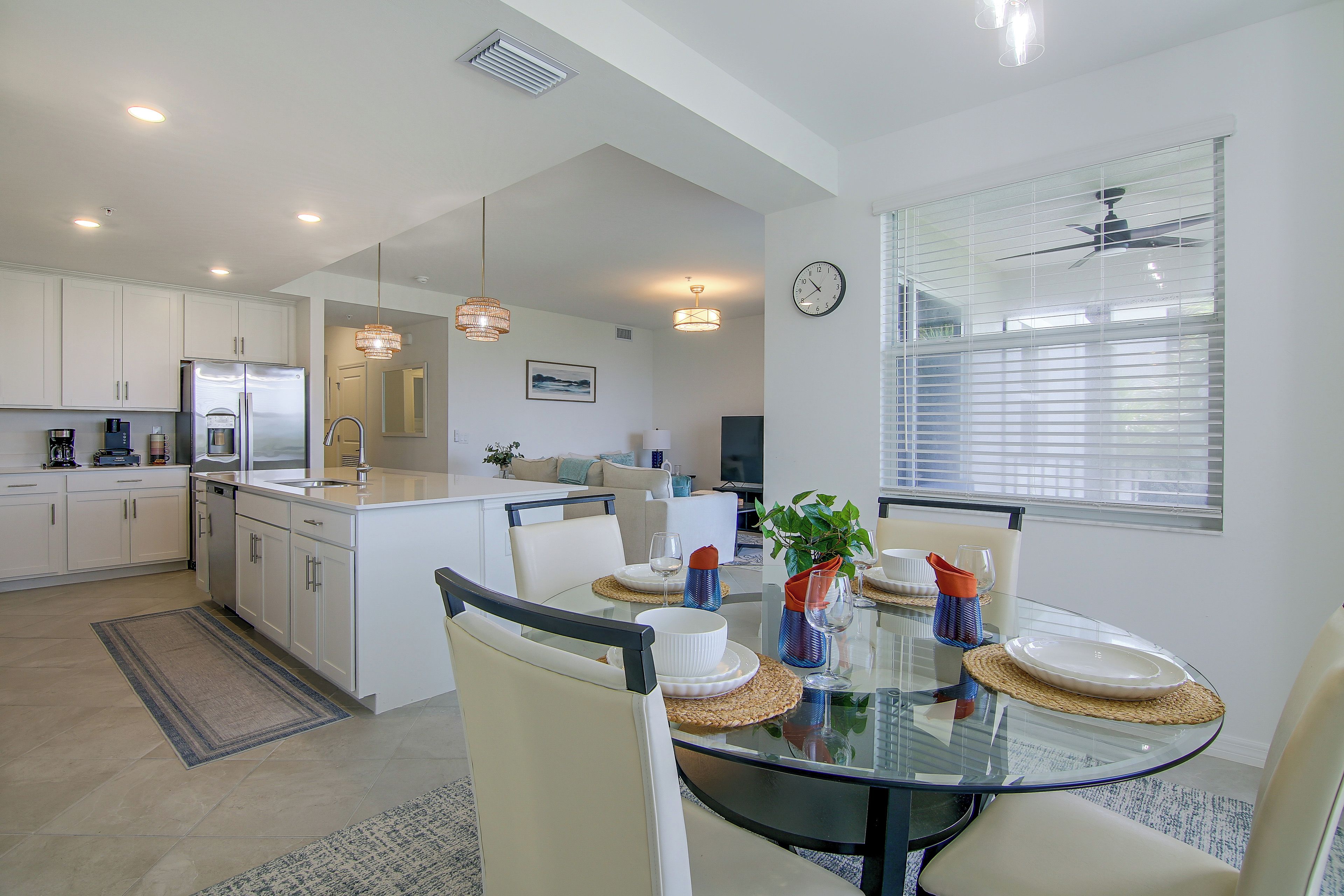A modern kitchen with white cabinets, a built-in refrigerator, and a dining area with a glass table and chairs.