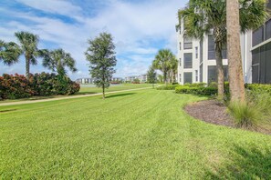 A well-maintained grassy area with a pathway leading to a modern building with multiple windows and balconies. - Pool Access! The National at Ave Maria Golf Escape (Immokalee)