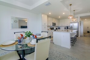 A modern kitchen with white cabinetry, a central island, and stainless steel appliances. - Pool Access! The National at Ave Maria Golf Escape (Immokalee)