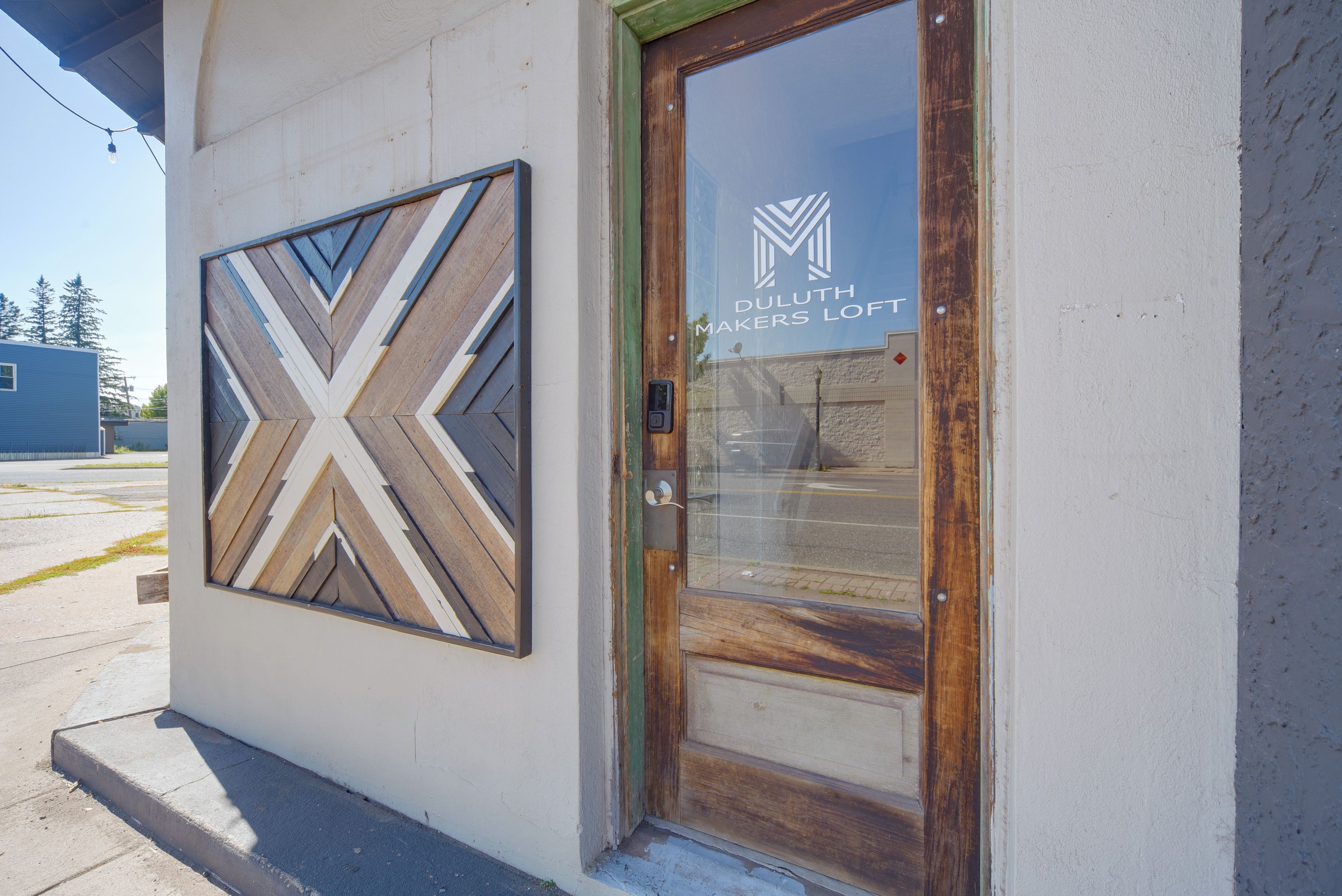 L’entrée d’un immeuble, avec une porte en bois et une fenêtre en verre sur laquelle est inscrit le nom « DULUTH MAKERS LOFT ».