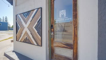 A building entrance with a wooden door and a glass window displaying the name 'DULUTH MAKERS LOFT'.