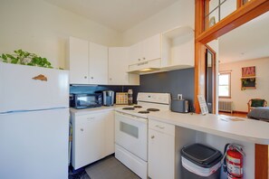 A compact kitchen with white cabinets, a stove, a microwave, and a coffee maker. - Charming Couple's Gem in Duluth w/ Enclosed Porch (Duluth)