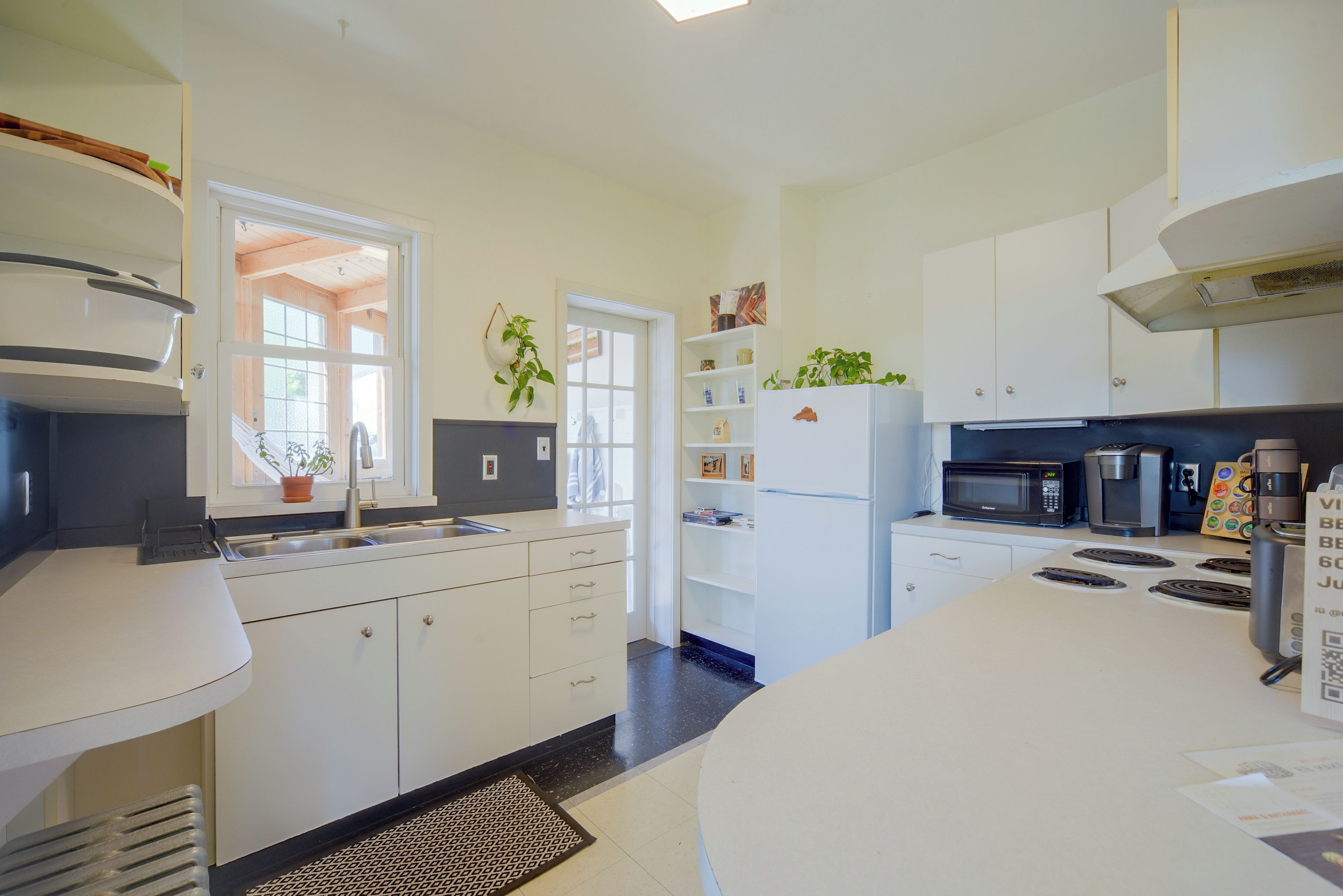A modern kitchen with white cabinets, a built-in oven, a microwave, and a refrigerator.