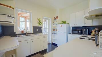 A modern kitchen with white cabinets, a built-in oven, a microwave, and a refrigerator.