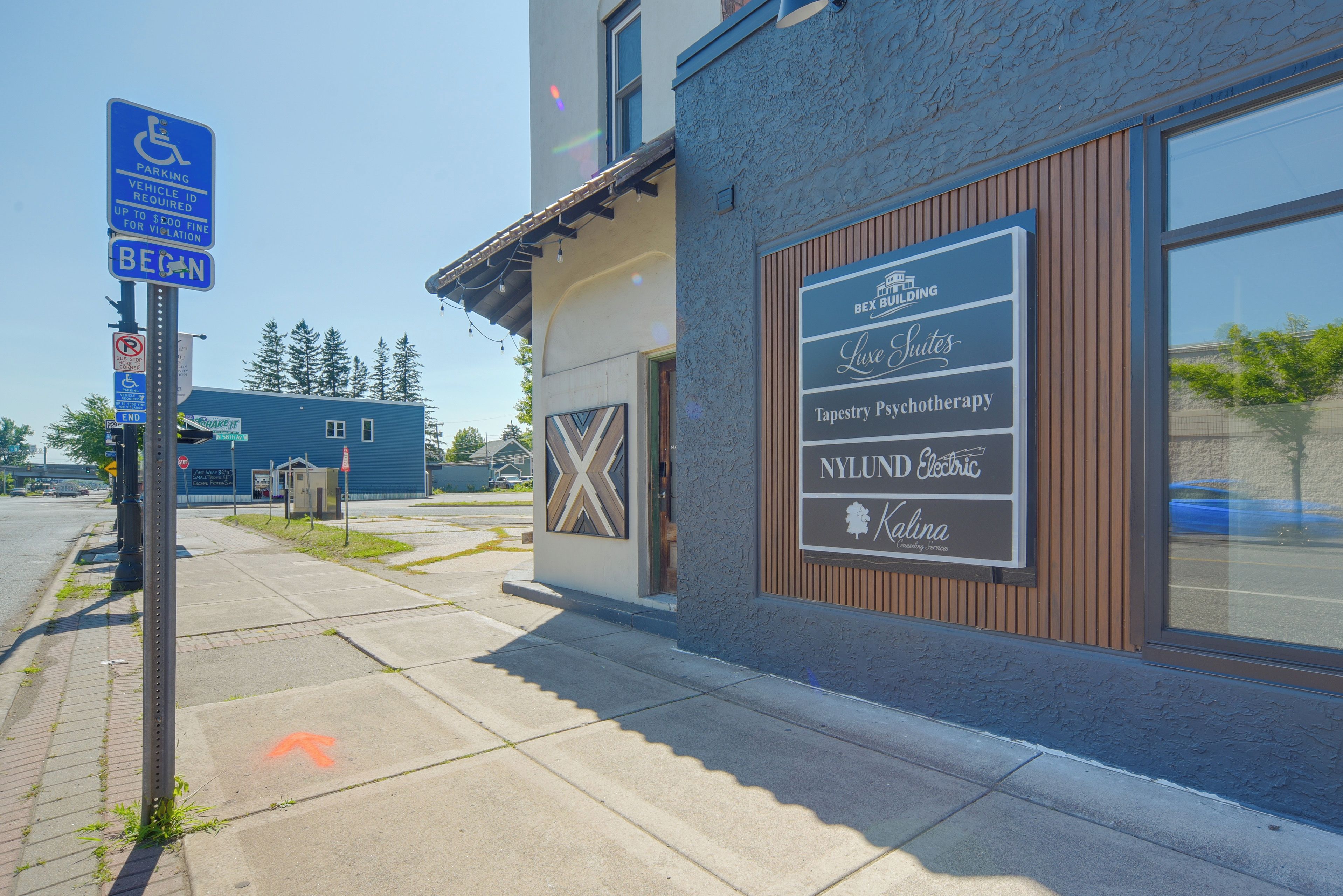 A building with a sign for Bex Building, Luxe Suites, Tapestry Psychotherapy, NYLUND Electric, and Kalina Counseling Services.