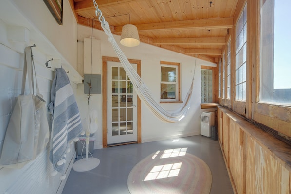 Una habitación con una hamaca, un ventilador y un ventanal grande.