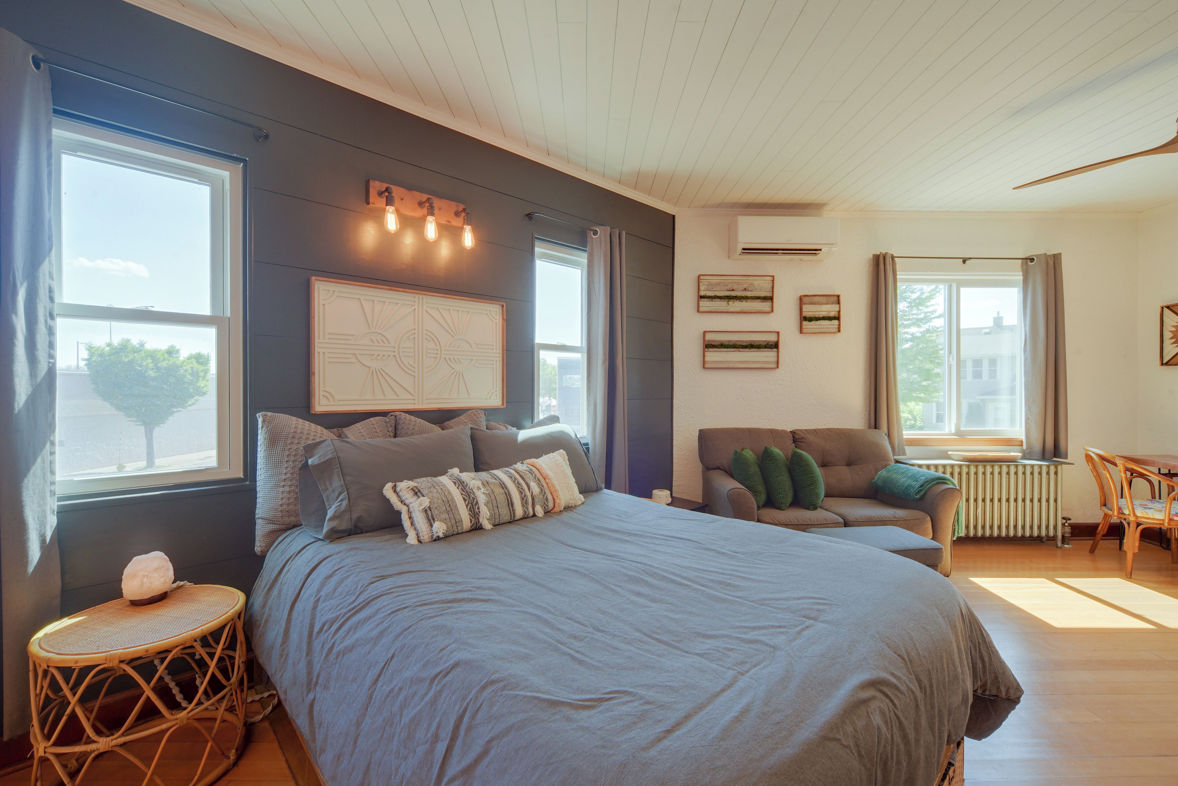 A bedroom with a large bed, a small table, a sofa, and a window with curtains.