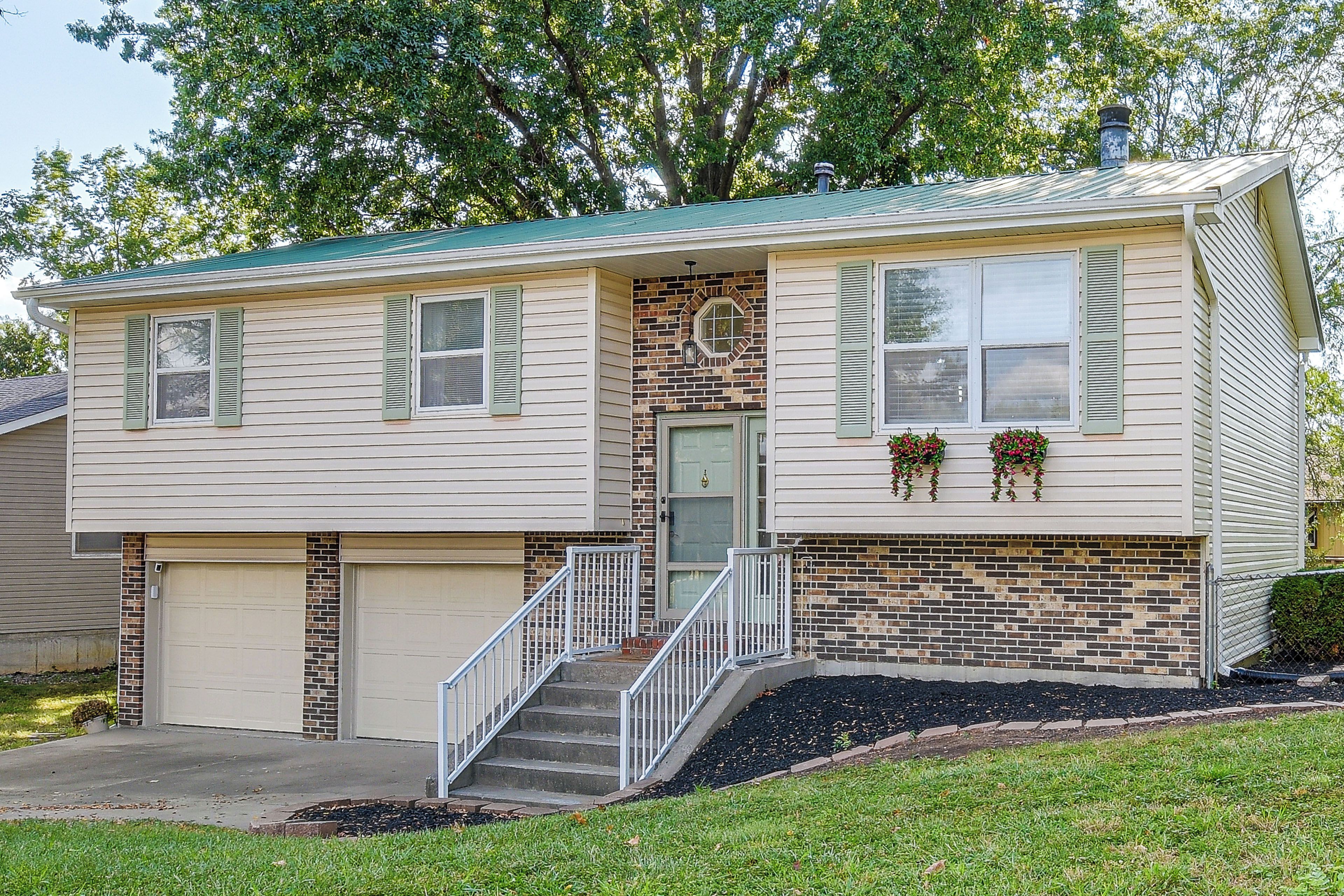 A two-story house with a front porch, a garage, and a brick accent wall.