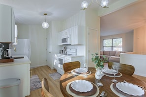 A modern kitchen with white cabinets, a built-in microwave, and a coffee machine.