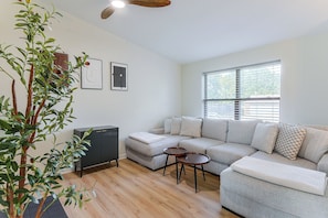 A modern living room with a sectional sofa, a small side table, and a dark-colored cabinet.