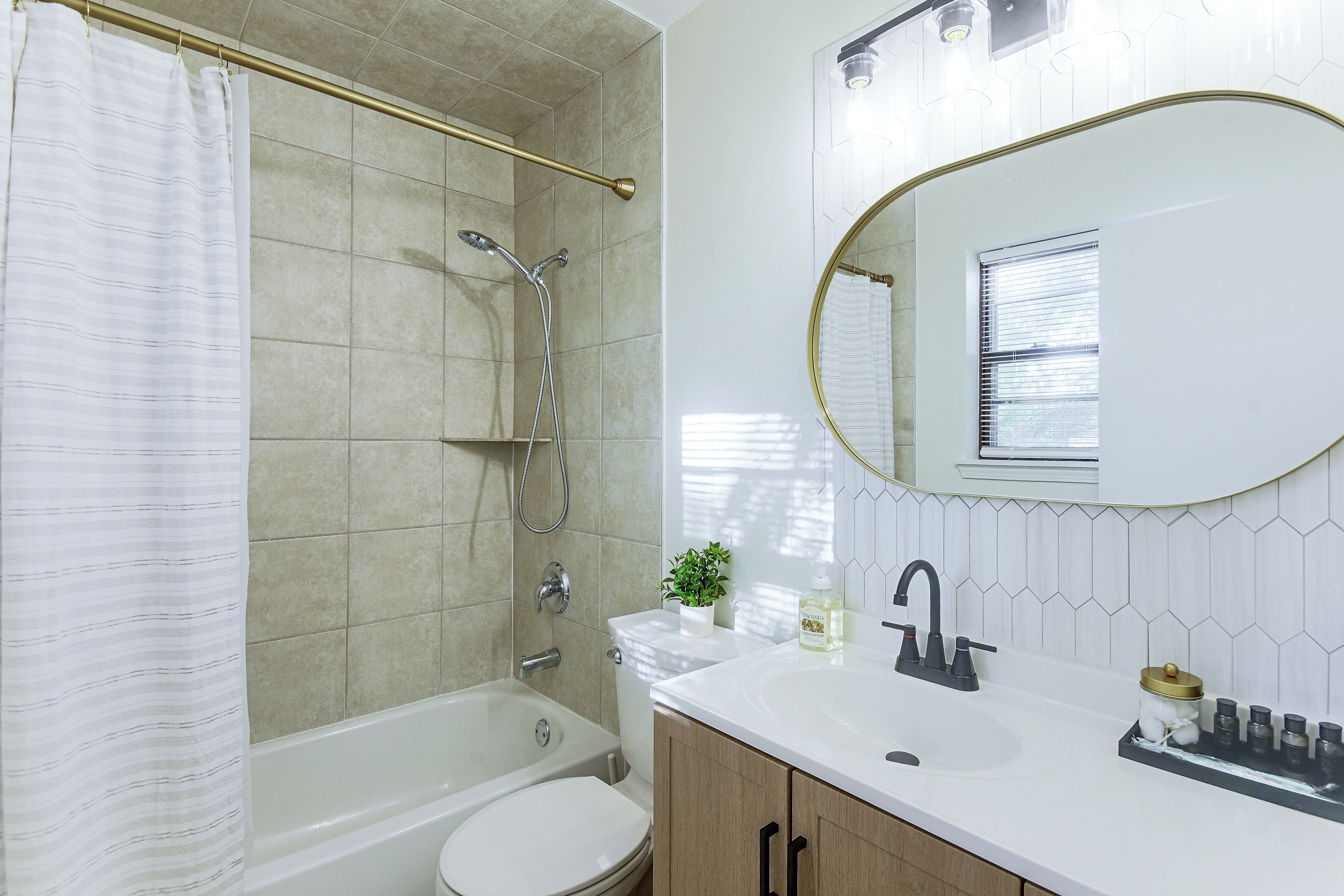 A modern bathroom with a bathtub, toilet, sink, and a shower with a handheld showerhead.