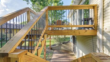 Una escalera de madera al aire libre que lleva a una terraza con barandilla de metal.
