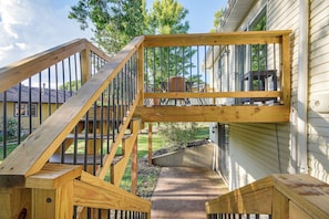 Un escalier extérieur en bois menant à une terrasse dotée d’une rambarde en métal.