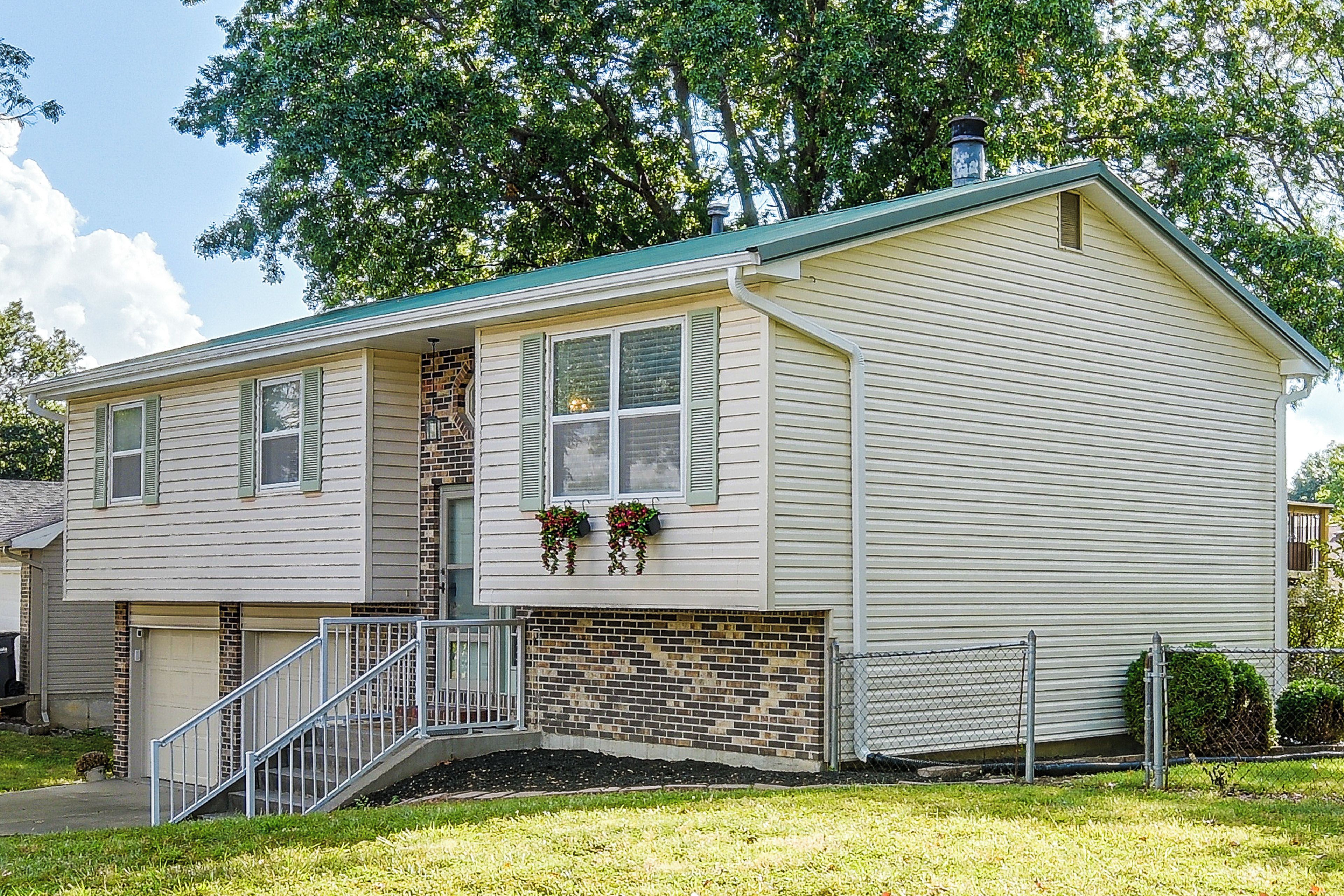 A two-story house with a front porch, a brick section, and a metal staircase.
