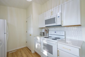 A kitchen with white cabinetry, a microwave, a stove, and a toaster.
